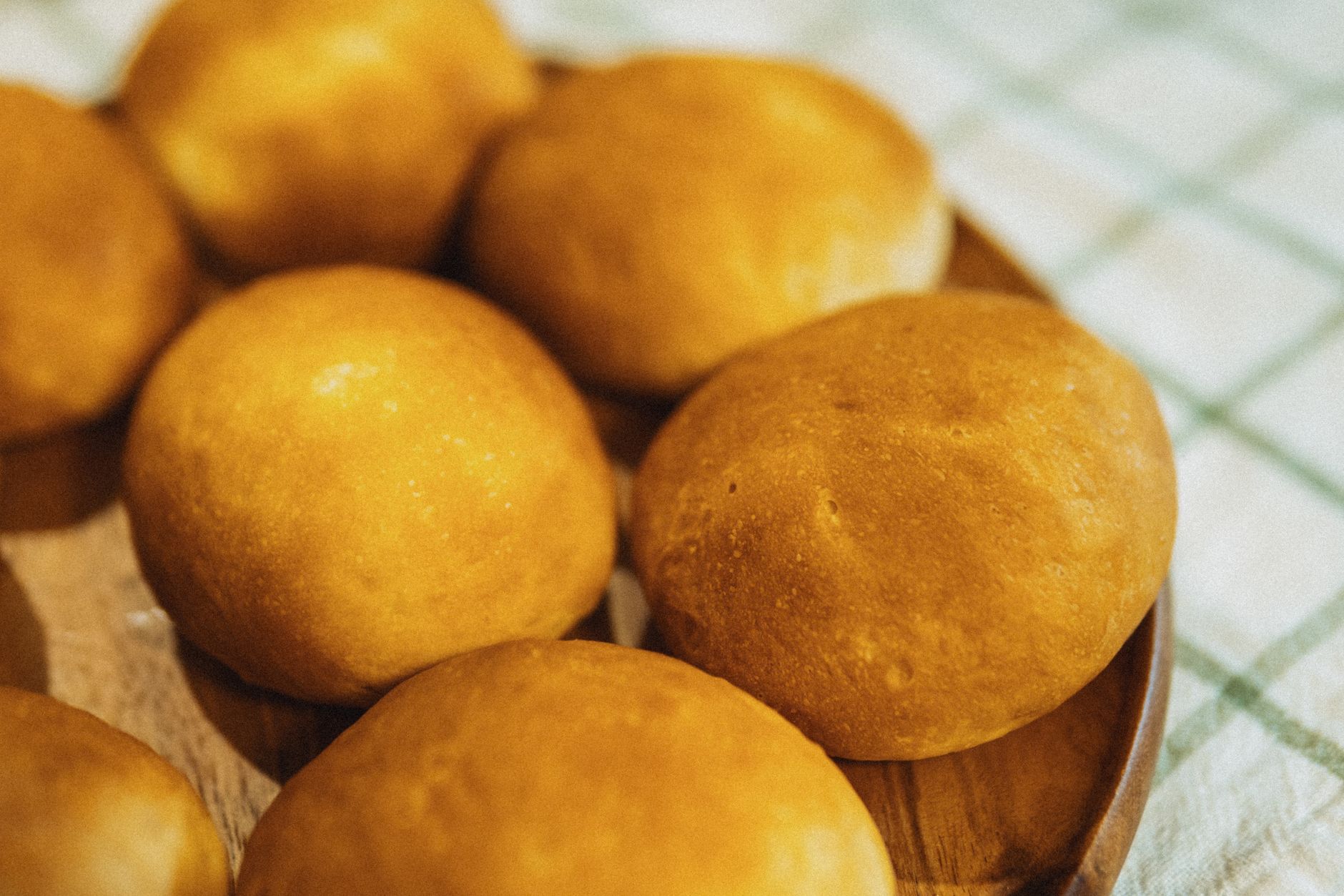 Golden brown bread rolls freshly baked and arranged on a wooden plate.